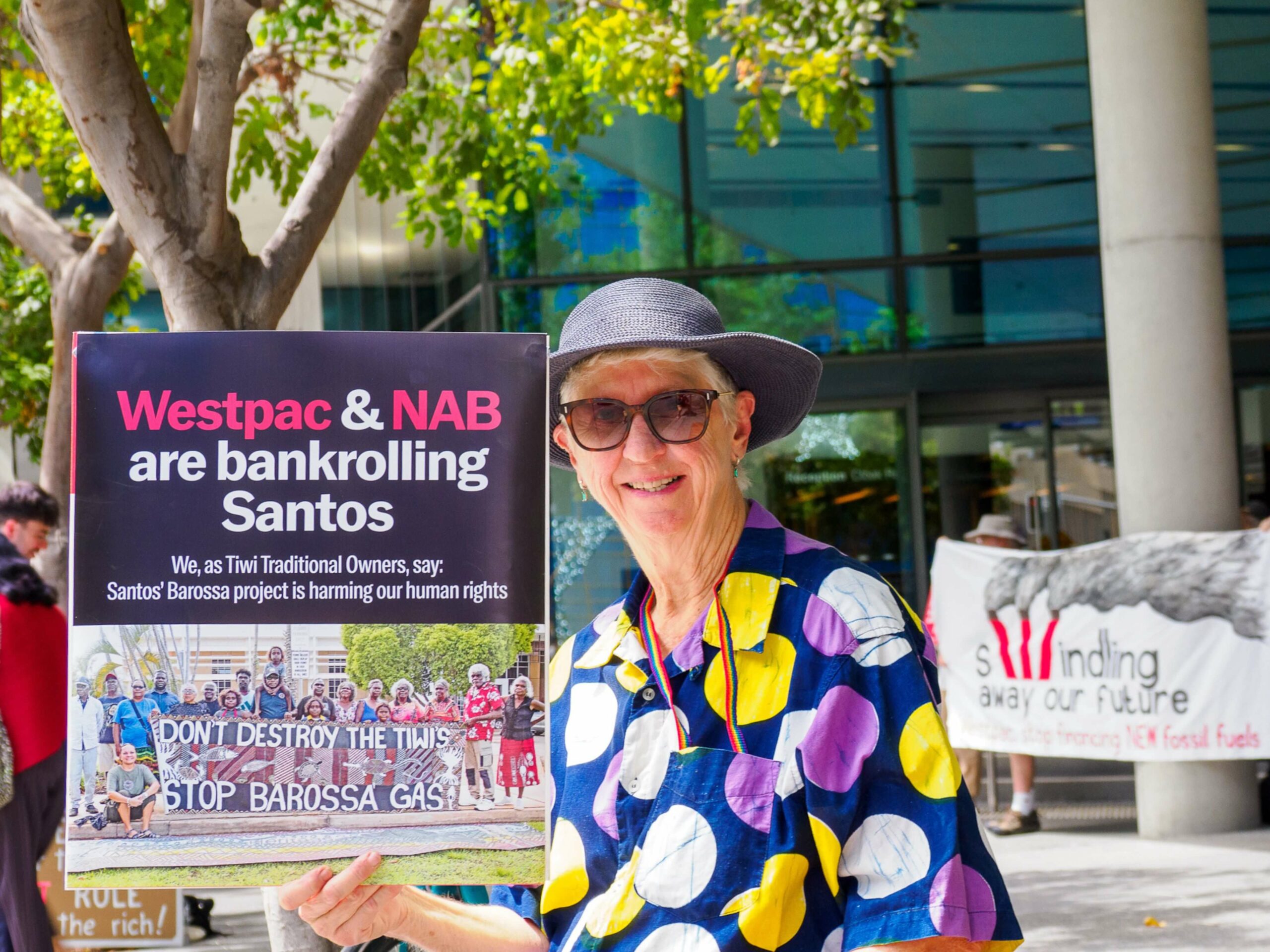 A women holds a sign that reads Westpac and Nabare bankrolling Santos outside the Westpac AGM 2023